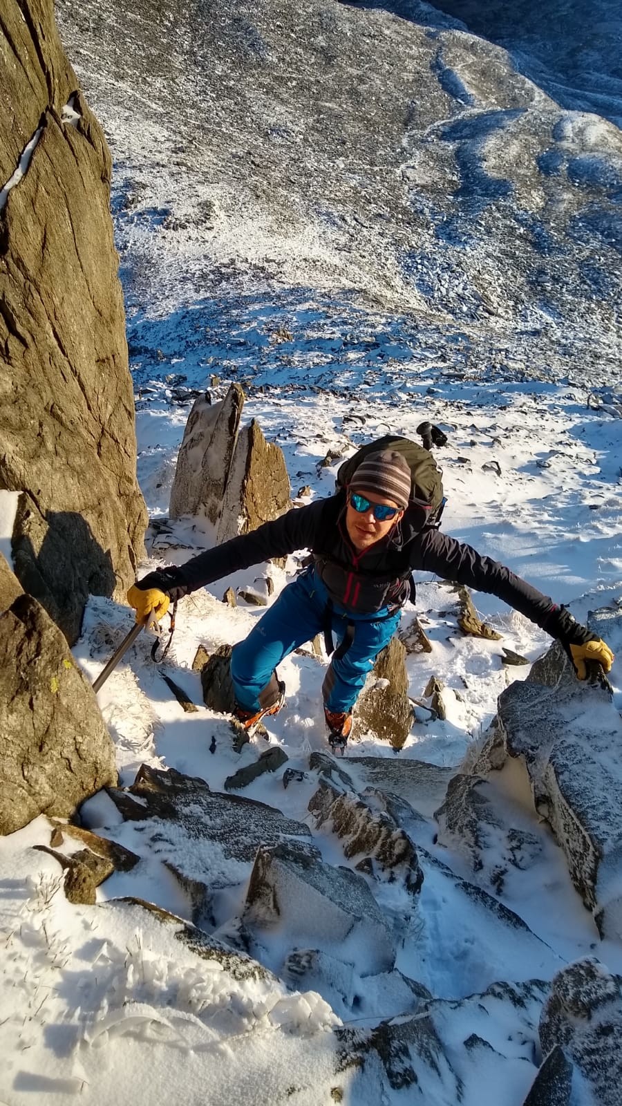 Me! Scrambling up a rocky mountain with a snowy field of scree behind. 