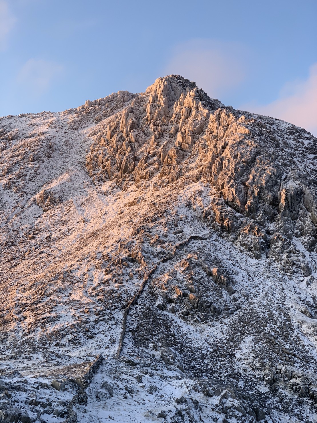 Gylder Fawr and Bristly Ridge during sunrise. This is a fairly prominent rocky outcrop with snow and ice covering most of it.